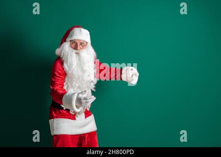 Acteur masculin émotif en costume de Père Noël avec une longue barbe gestante sur fond vert studio Banque D'Images