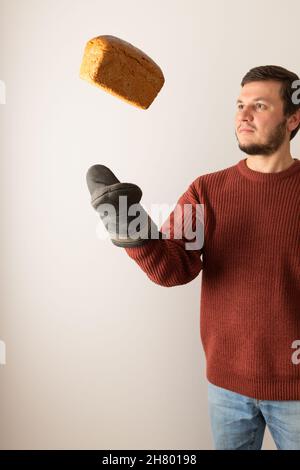 Un homme dans un chandail jette un pain de seigle dans l'air.Vue avant.Portrait. Banque D'Images