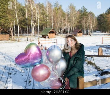 Portrait d'une jeune fille tendre et mignonne, fille d'anniversaire, 16-17 ans, tenant beaucoup de ballons colorés dans ses mains. Beau jour d'hiver. Se sent super, fe Banque D'Images