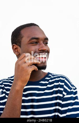 Beau homme américain africain barbu dans une chemise rayée élégante, debout sur fond blanc en ville Banque D'Images