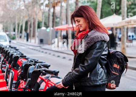 Femme dans le parking public de vélos de location. Banque D'Images