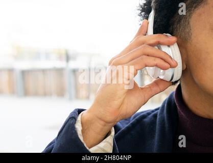 Rognez un homme afro-américain méconnaissable sur un casque sans fil moderne pour écouter de la musique Banque D'Images