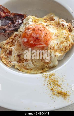 Vue en hauteur des œufs savoureux avec des tranches de bacon frites sur l'assiette Banque D'Images