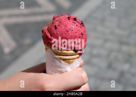 Cône de crème glacée à la main.Dessert aux fruits rouges surgelés roses. Banque D'Images