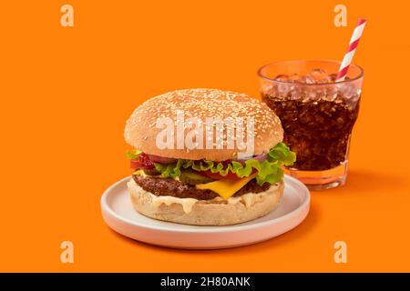 Hamburger frais savoureux et boisson non alcoolisée sur fond orange Banque D'Images