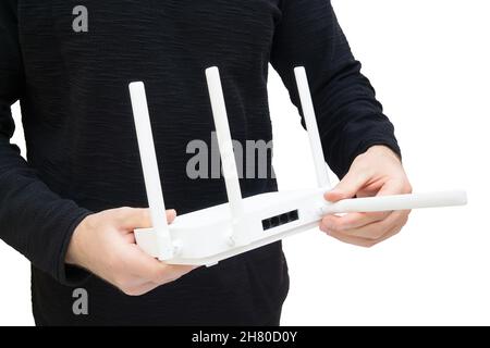 Homme tenant un routeur Wi-fi 6 double bande moderne et pointant vers l'une des antennes.Amélioration de la couverture et du signal grâce à un positionnement optimal. Banque D'Images