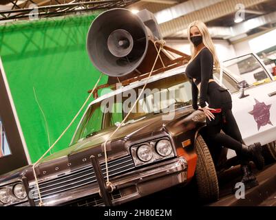 Essen, Allemagne.26 novembre 2021.Un modèle pose devant une voiture de police Dodge du film « Blues Brothers » au salon de l'tuning « Essen Motor Show ».Environ 400 exposants souhaitent présenter des véhicules et des accessoires dans huit halls de 27.11 à 05.12.2021.Crédit : Roland Weihrauch/dpa/Alay Live News Banque D'Images