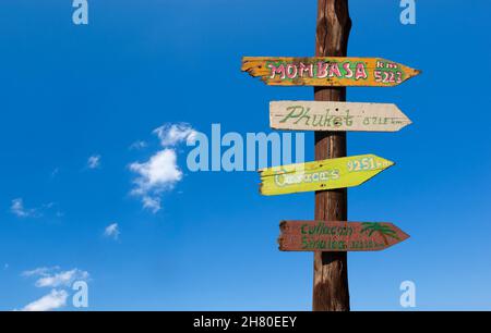 Panneaux en bois colorés avec des distances à d'autres villes contre un ciel bleu Banque D'Images