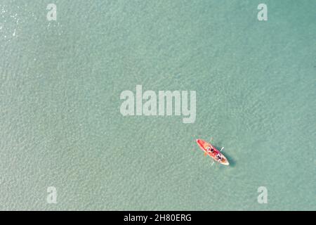 Vue aérienne de la mer bleue avec couple et kayak flottant coloré va dans la plage de sable, personne avec gilet de sauvetage sur bateau Banque D'Images