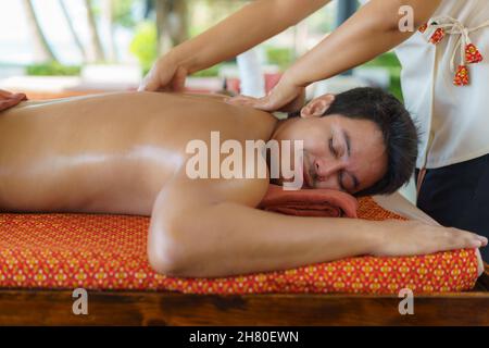 Homme asiatique au spa de la plage se faire masser à l'huile près de la plage et se faire plaisir en Thaïlande.Spa, complexe, beauté et concept de santé. Banque D'Images
