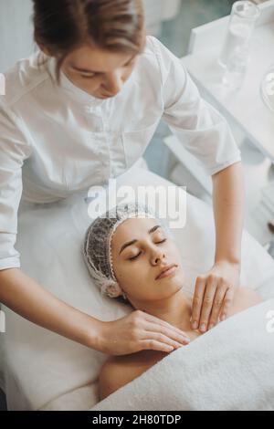Masseuse faisant manuellement relaxant massage rajeunissant épaules pour femme dans le salon de beauté.Massage relaxant.Procédure de beauté de cosmétologie. Banque D'Images