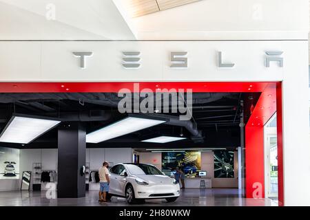 Miami, États-Unis - 19 juillet 2021 : panneau pour magasin Tesla avec des gens clients qui cherchent voiture électrique à l'intérieur du centre commercial Aventura dans florid Banque D'Images