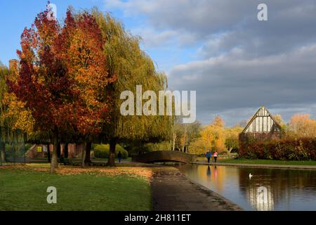 Scène urbaine ensoleillée et automnale (couple de marche, réflexions sur l'eau, pont) - pittoresque parc municipal ensoleillé Rowntree Memorial Park, York, Angleterre, Royaume-Uni. Banque D'Images