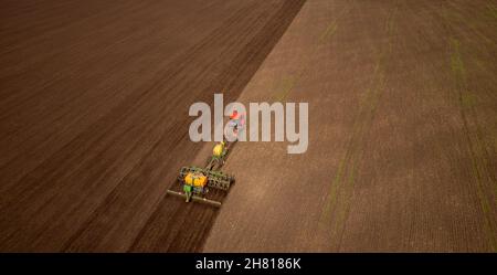 Un agriculteur sur tracteur cultive et charrue des terres de champ pour la plantation de céréales .Vue aérienne du dessus Agriculture concept. Banque D'Images