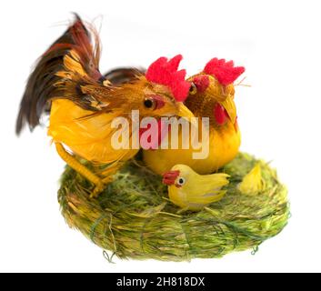 Coq, poule et poussin dans un nid d'herbe - jouet de Pâques isolé sur fond blanc. Banque D'Images