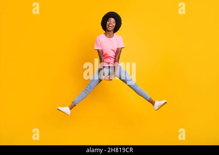 Photo pleine grandeur de joyeuse femme jump porter rose t-shirt Jean isolé sur fond jaune Banque D'Images