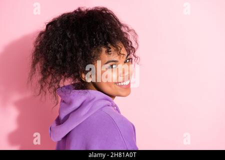 Photo de drôle douce africaine dame vêtue violet hoodie souriant espace vide isolé couleur rose fond Banque D'Images