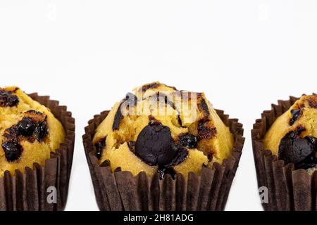 Délicieux muffins à la vanille et au chocolat frais faits maison dans un porte-gâteau en papier isolé sur fond blanc.Avec espace de copie pour les textes. Banque D'Images