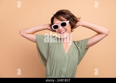 Photo de charmante jeune femme joyeuse temps libre danse porter soleil glass frais isolé sur fond beige couleur Banque D'Images