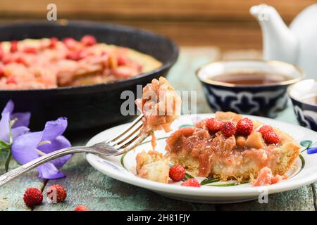 Tarte rustiques à la rhubarbe avec des fraises de forêt fraîches mangées avec une fourchette melchior vintage Banque D'Images