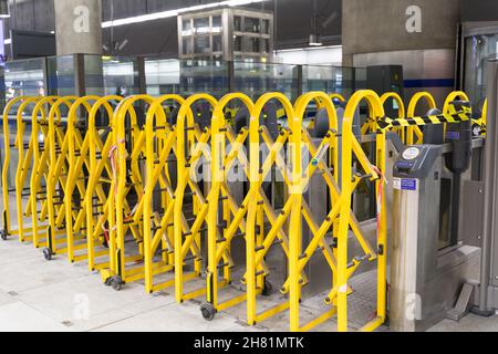 Londres, Royaume-Uni. 26 novembre 2021. La barrière jaune de contrôle de foule est tracée à travers l'entrée de la gare de Canary Wharf tandis que RMT prend 24 heures de grève industrielle sur cinq lignes de métro londoniennes, dans un différend sur de nouveaux modèles de changement de vitesse alors que le service de métro de nuit devrait reprendre ce week-end. Crédit : Xiu Bao/Alamy Live News Banque D'Images