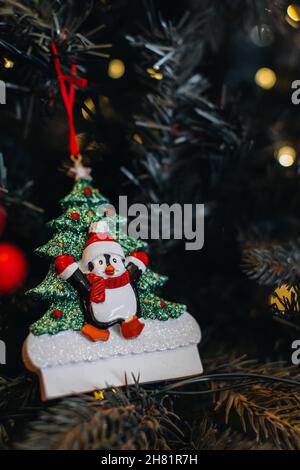 Figurine jouet de Noël de pingouin drôle dans un chapeau de Père Noël accroché aux branches de l'arbre de Noël.Détails magiques pour les fêtes de la nouvelle année Banque D'Images