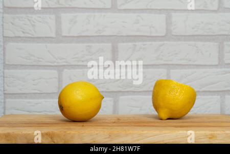 Deux citrons jaune vif sur la table avec le mur de briques sur le fond Banque D'Images