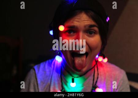 Flou artistique du portrait de Noël.Gros plan fou bonne jeune femme célébrant noël.Les jeunes s'amusent et montrent la langue.Femme enveloppée de couleur Banque D'Images