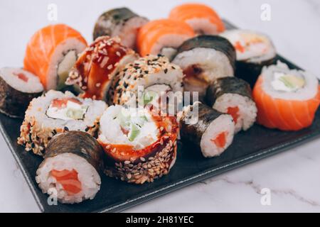 Menu du bar à sushis pour le déjeuner - différents petits pains à sushis avec saumon, avocat et anguille smockée sur fond de table en marbre blanc avec espace pour les copies - futomaki. Uramaki Banque D'Images