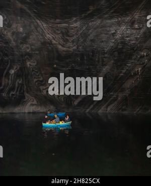 Turda, Roumanie-24 août 2021: Photo de l'intérieur de la mine de sel de Turda, dans laquelle les gens peuvent être vus dans les bateaux sur le lac entouré par des murs de sel Banque D'Images