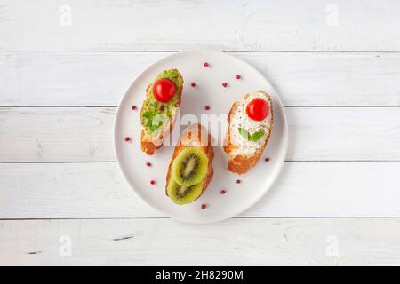 Trois mini sandwiches sur une assiette sur fond de bois Banque D'Images