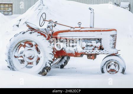 Un vieux tracteur antique recouvert de neige. Banque D'Images