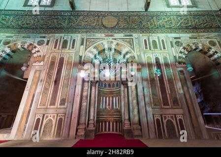 Mihrab de la chambre du mausolée à la Mosquée historique de l'époque Mamluk et Madrasa du Sultan Hassan avec mosaïque de marbre multicolore, et inscription sculptée du verset du trône, le Caire, Égypte Banque D'Images