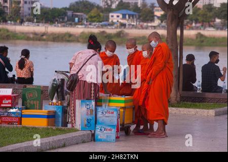 4 jeunes moines novices, portant des masques protecteurs, achètent des boissons au bord de la rivière pendant le Festival de l'eau cambodgien. Les courses de bateaux ont été annulées pour la 2e année consécutive en raison de la pandémie COVID - 19.Phnom Penh, Cambodge.20 novembre 2021.© Kraig Lieb Banque D'Images