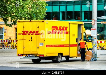 La fourgonnette logistique DHL est déchargée sur la piste de la gare par un employé muni d'un camion à main à Hanovre, en Allemagne, le 23 mai 2020. Éditorial Banque D'Images