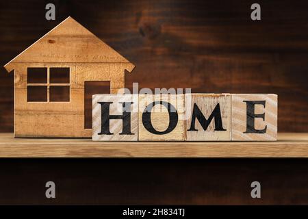 Text Home fait de blocs de bois et d'une petite maison modèle sur une étagère en bois avec espace de copie. Banque D'Images