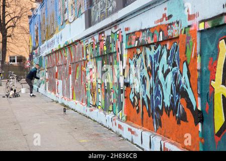 Pulvérisateur de graffiti mâle colorant un mur à l'extérieur de l'abattoir (Schlachthofviertel), Munich, Bavière, Allemagne. Banque D'Images