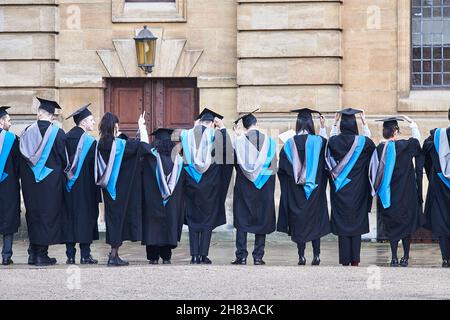 Des étudiants granduates couronnés de succès se présentent dans le quadrilatère Clarendon de la cour Bodléienne après la cérémonie de remise de leur diplôme au théâtre Sheldonian de l'université d'Oxford, le 26 novembre 2021, sur une surface humide. Banque D'Images