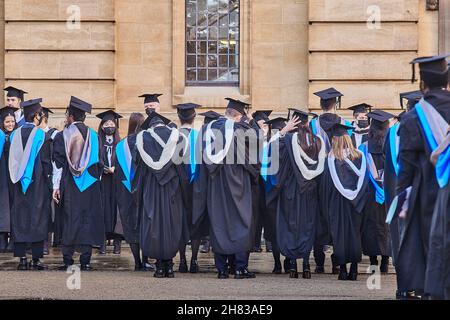 Des granduates couronnées de succès s'alignent dans la section Clarendon de la cour Bodleian après la cérémonie de remise de leur diplôme au théâtre Sheldonian de l'université d'Oxford, le 26 novembre 2021, sur une peau humide. Banque D'Images