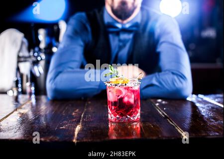 Un barman professionnel crée un cocktail tout en se tenant près du comptoir du bar Banque D'Images
