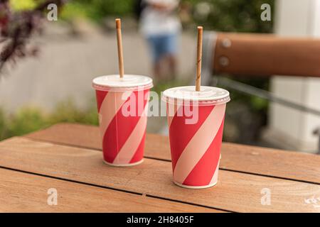 Deux tasses roses de boisson non alcoolisée avec pailles en papier sur une table Banque D'Images