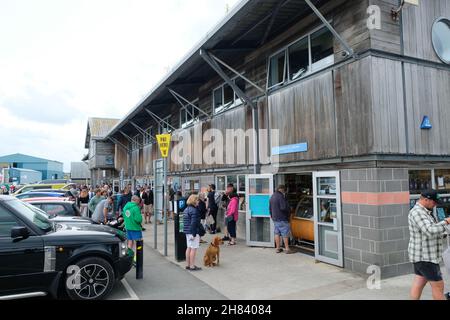 Padstow, Royaume-Uni - juillet 2021 : les clients font la queue devant Stein's Deli, au bord de la rivière Padstow. Banque D'Images