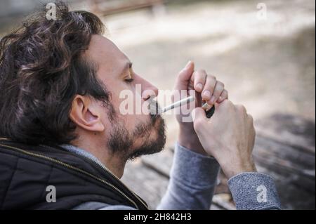 Homme éclairant une cigarette conjointe de marihuana ou de haschisch.Vue de détail en gros plan.Les jeunes fument du cannabis thc herbe.Concept de scène de la vie réelle Banque D'Images