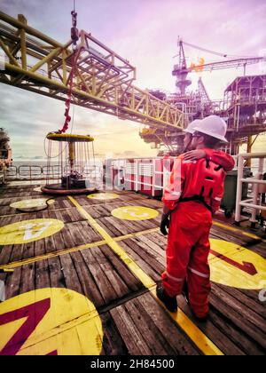 les membres de l'équipage se tiennent debout pendant le transfert de l'équipage de la plate-forme au bateau à équipage rapide en passant par un panier personnel de sécurité à l'intérieur d'une zone de 500 mètres Banque D'Images