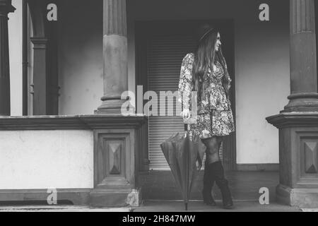 Photo en niveaux de gris d'une jeune femme caucasienne posant pour un photoshoot au milieu de l'entrée. Banque D'Images