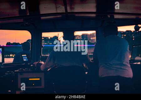 Vie arrière de deux hommes pilotant un bateau vers un coucher de soleil sur la tamise dans le centre de Londres Banque D'Images