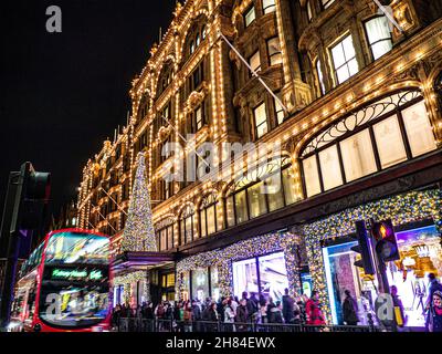 NOËL LONDRES LUMIÈRES DE SHOPPING HARRODS BLUR OCCUPÉ MAGASIN DE LONDRES Harrods au crépuscule avec des foules de shopping de lumières de Noël et en passant le bus rouge Knightsbridge Londres SW1 Banque D'Images