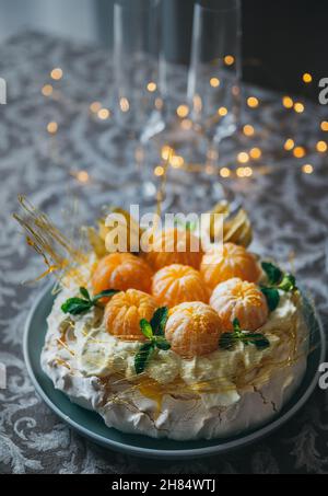 Le gâteau Pavlova est un dessert à base de meringue nommé d'après la ballerine russe décorée de mandarines fraîches, de caramel, de menthe, de physalis et de suga en poudre Banque D'Images