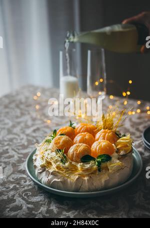 Le gâteau Pavlova est un dessert à base de meringue nommé d'après la ballerine russe décorée de mandarines fraîches, de caramel, de menthe, de physalis et de sucre en poudre Banque D'Images