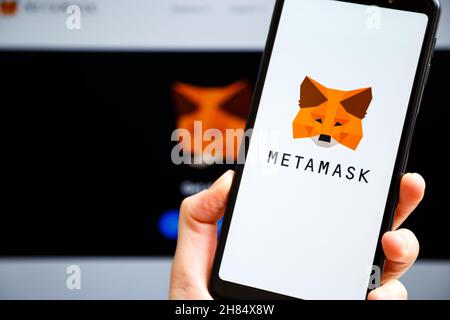 Ukraine, Odessa - octobre, 9 2021: Main tenant mobile avec l'application MetaMask en cours d'exécution à l'écran de smartphone avec metamask.io site Web en arrière-plan.MetaMask Banque D'Images